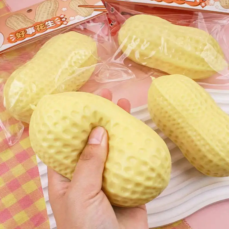 Large yellow peanut-shaped items with a hand holding one, on a checkered background.