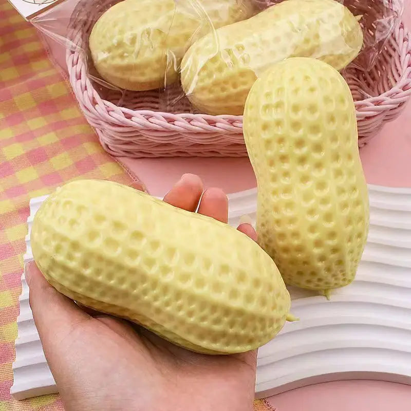 Yellow squish Peanut shaped like fidget toys on a pink checkered tablecloth.