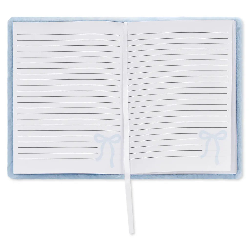 An open lined notebook with a soft light blue cover and a white ribbon bookmark, shown on a plain white background.