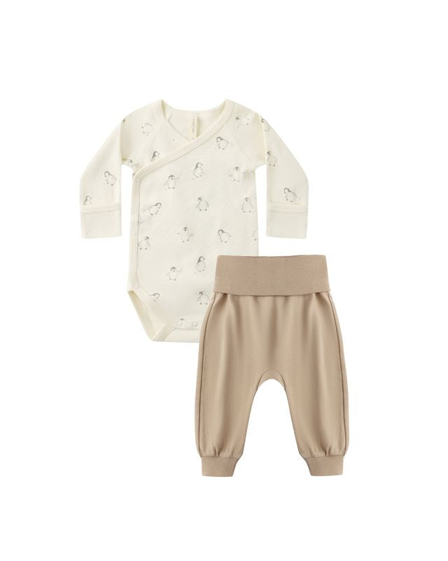 Baby outfit set with cream onesie with penguins on it and beige pants on a white background