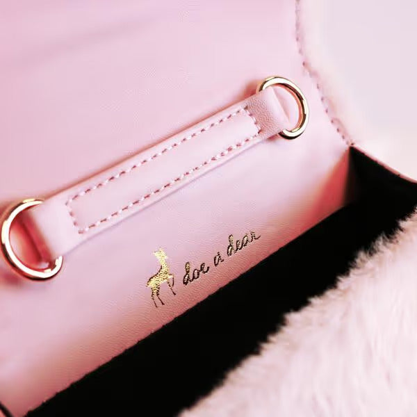 Close-up of a pink product with ' Doe & Bear' branding on a soft background