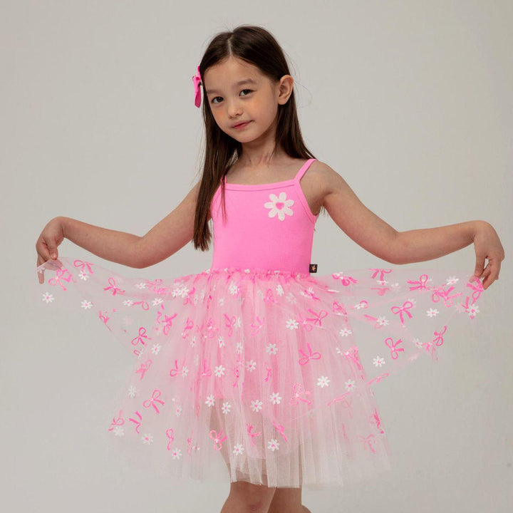 young girl modeling the hot pink tutu dress. the girl is pulling the tulle skirt up to see the details on the skirt better. 