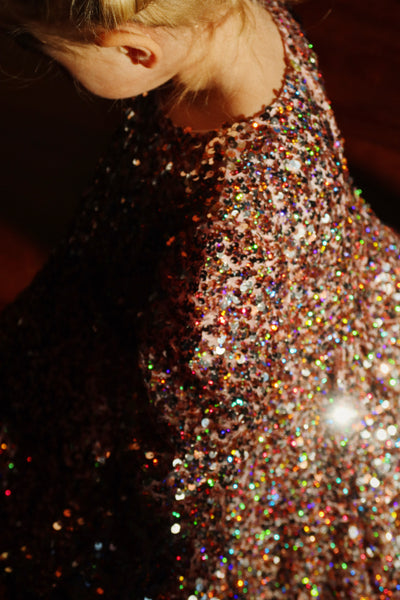 this picture has a little girl modeling the pink sequin dress. it shows light hitting the dress and all the colors the sequins show. The color of the sequins is pink, more of a dusty rose. 