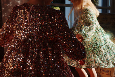 this picture shows two little girls dancing at night. the light bounces off of the sequins! One little girl has a pink dress on and the other a light green. 