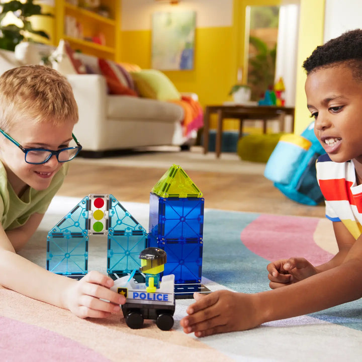 Two children playing with magnetic building blocks in a colorful living room.