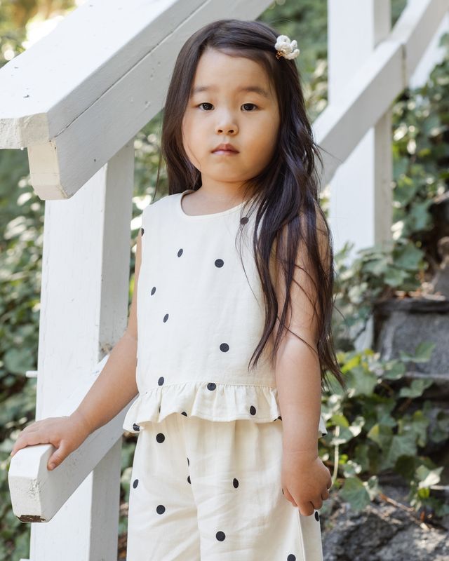 close up to the ivory outift with black polka dots all over. Little girl wearing the set. 