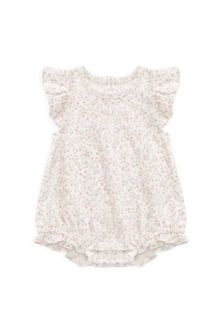 A baby girl's short-sleeve romper in a warm cream or off-white fabric with a delicate, all-over small floral print in muted pink and beige. The romper features ruffled cap sleeves and a ruffled hem, photographed flat against a solid white background.