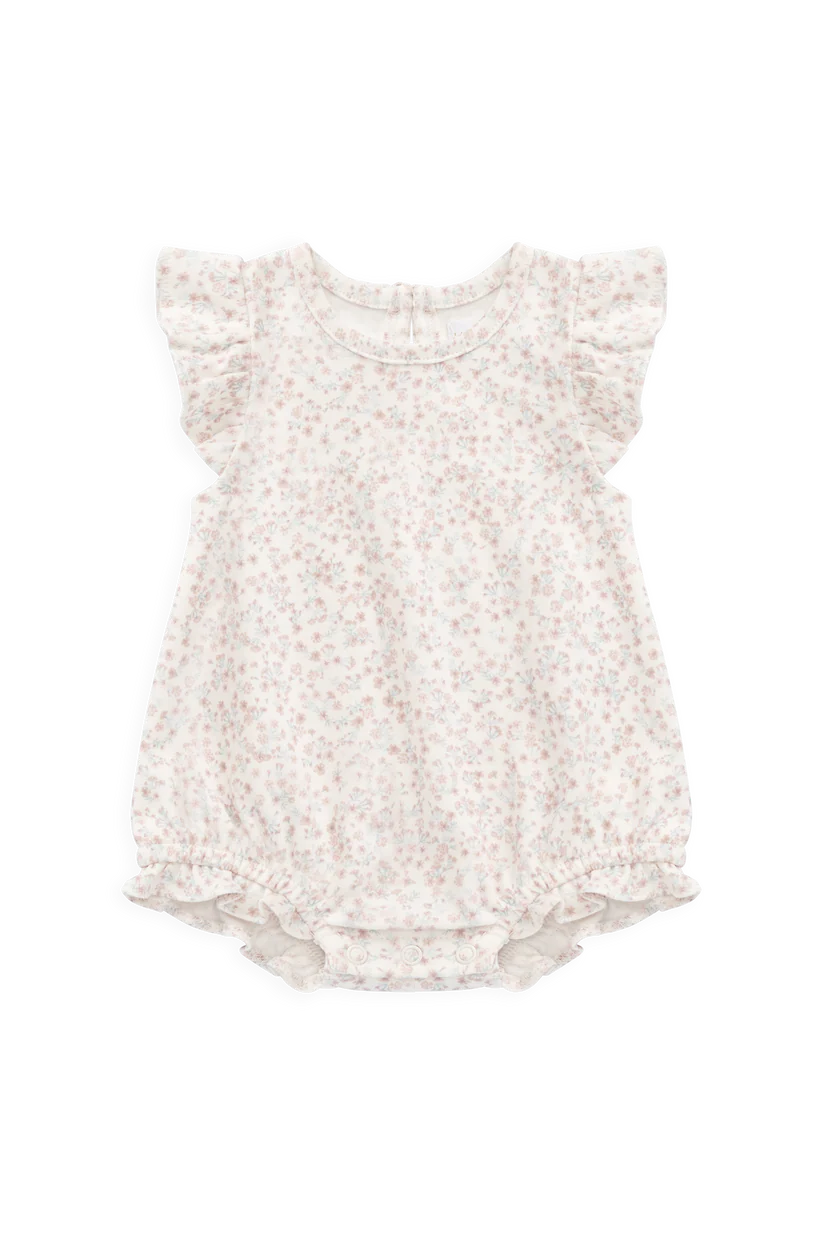 A baby girl's short-sleeve romper in a warm cream or off-white fabric with a delicate, all-over small floral print in muted pink and beige. The romper features ruffled cap sleeves and a ruffled hem, photographed flat against a solid white background.
