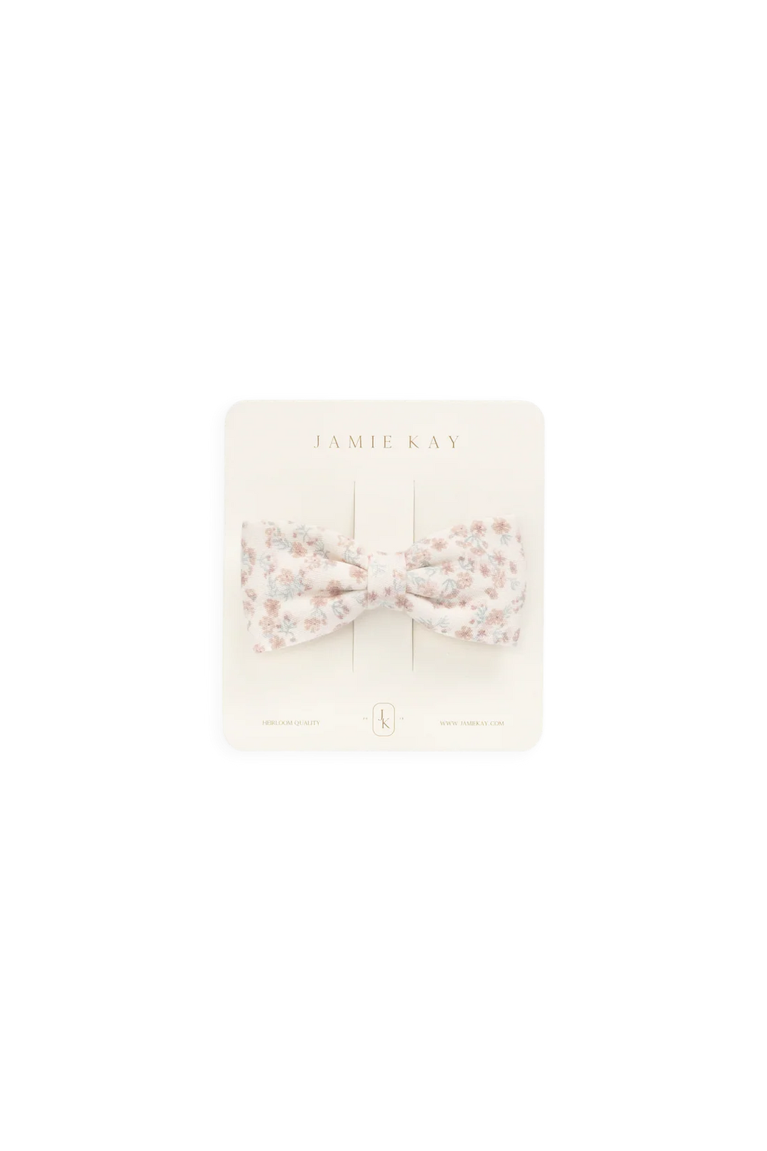 A small bow-shaped hair accessory with a delicate floral print in soft pink, beige, and white, presented on a cream-colored display card labeled 'JAMIE KAY'.