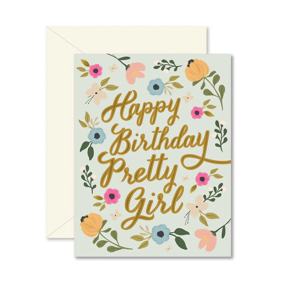A floral birthday card with gold foil lettering that reads 'Happy Birthday Pretty Girl,' shown with a cream envelope behind it on a white background.