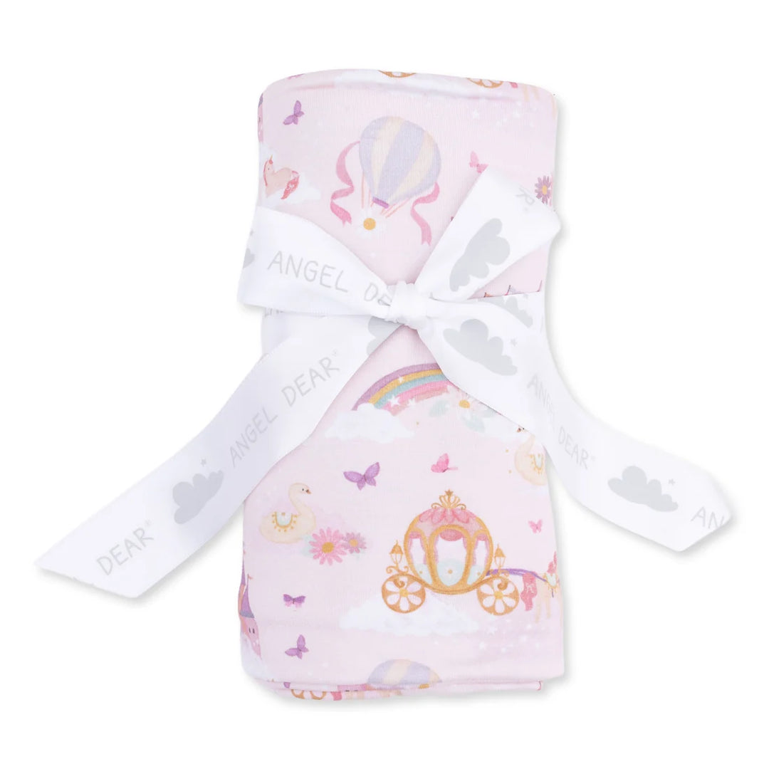 A pink baby blanket with a whimsical print of hot air balloons, a carriage, butterflies, and clouds, tied with a white ribbon printed with 'DEAR ANGEL'.