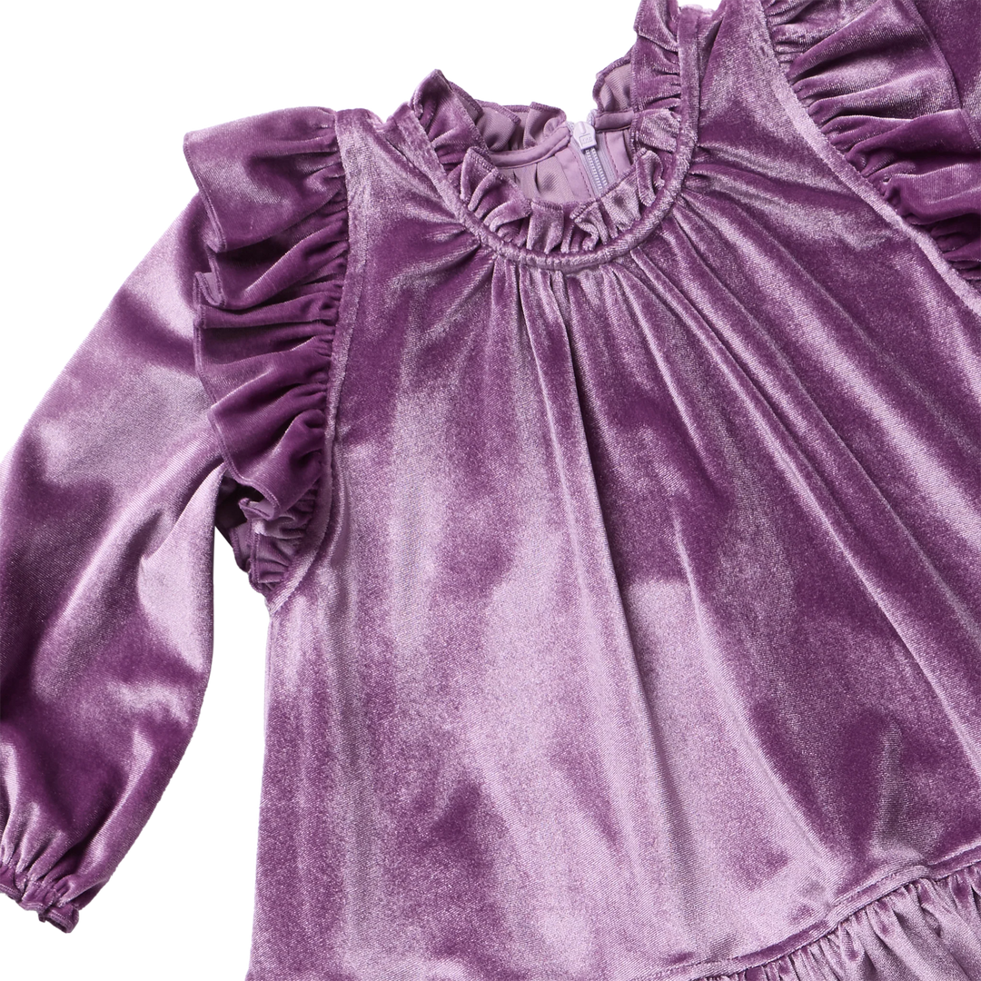 close up of the texture and color of the purple velvet dress with ruffles at each shoulder. 
