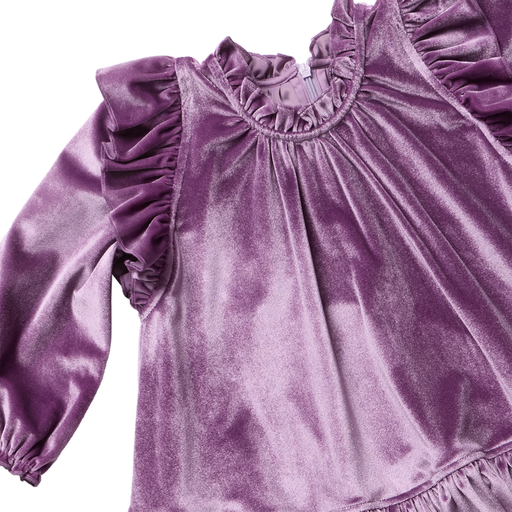 close up of the texture and color of the purple velvet dress with ruffles at each shoulder. 