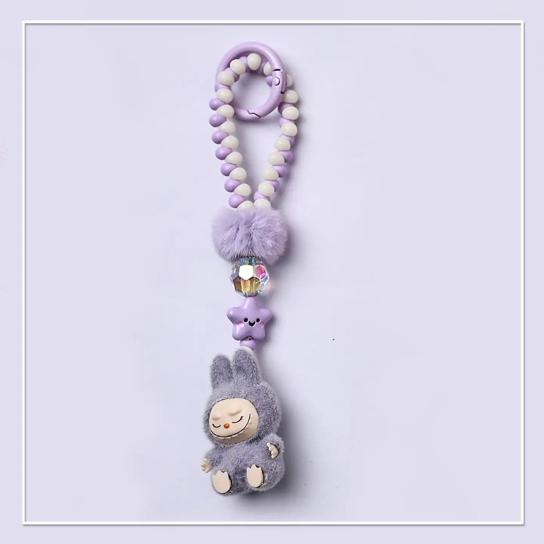 Plush keychain with pom-pom beads on a light purple background