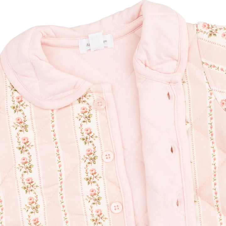 Close-up of a light pink quilted button-front garment with floral embroidered vertical stripes and a rounded collar on a white background.