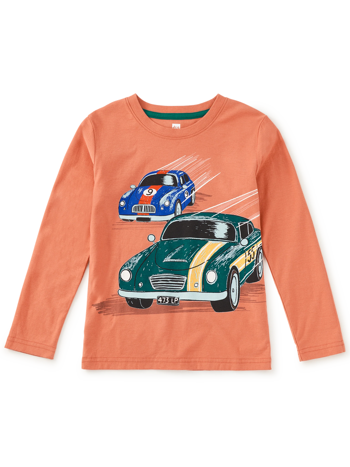 A children's long-sleeve t-shirt in a warm peach-orange color, featuring a graphic print of two vintage racing cars (a green MG with yellow stripes and a blue sports car) on a white background.