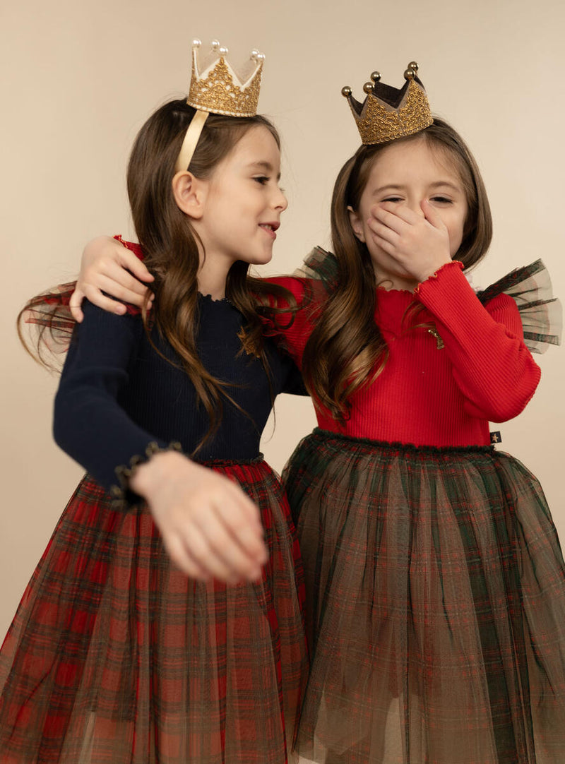 little girls modeling the Holiday tulle dresses. one dress has a red top and one dress has a navy top. each girl is wearing a crown and looking festive. 