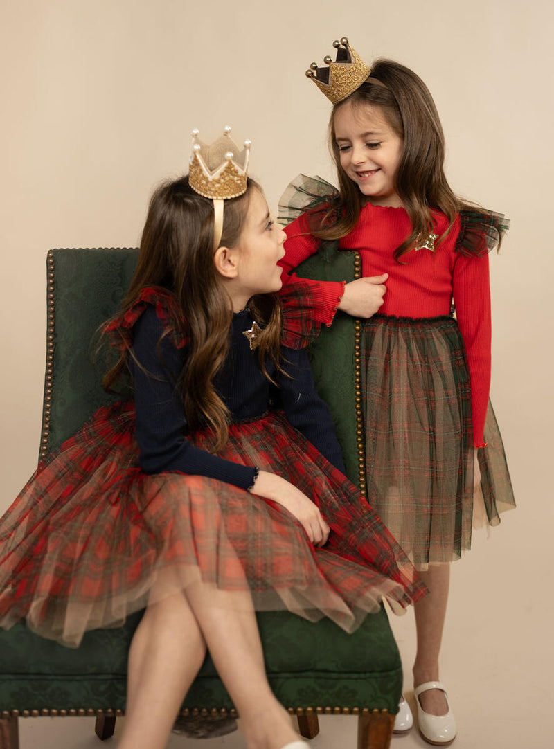 the little girls are wearing holiday dresses with red top and black and red plaid tulle bottom. the other girl is wearing a navy dress with red and navy tulle bottom. 