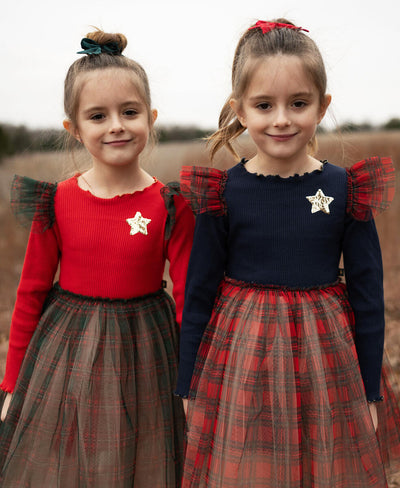 2 little girls wearing holiday dresses with tulle plaid bottoms. 