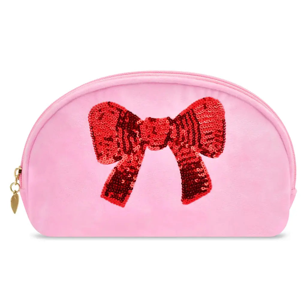 A pink zippered cosmetic pouch featuring a large, sequined red bow on the front, with a gold-tone zipper pull on the left side.