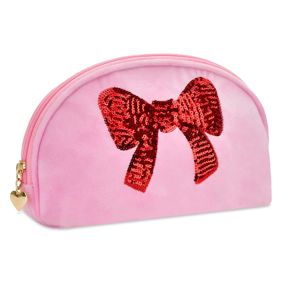 A pink velvet cosmetic pouch with a large red sequined bow on the front, featuring a gold zipper and a small gold heart charm.