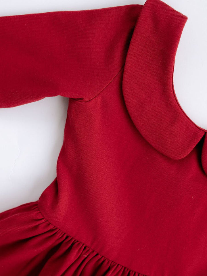 A close-up of a red long-sleeve dress with a wide Peter Pan collar and gathered skirt, shown on a white mannequin torso against a white background.