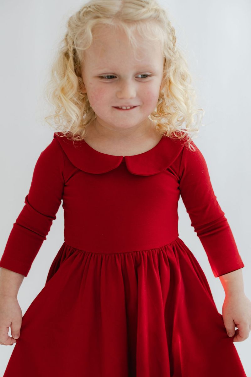 Young girl wearing a red dress with a white background