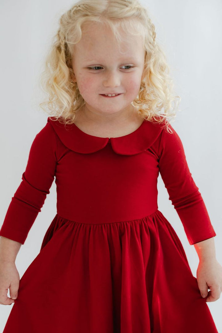 Young girl wearing a red dress with a white background