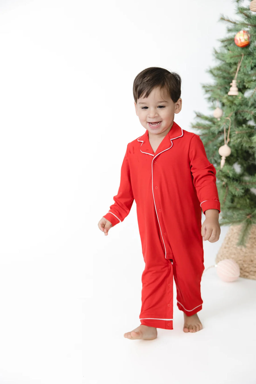 young toddler wearing red romper pajama with snaps down the front. 