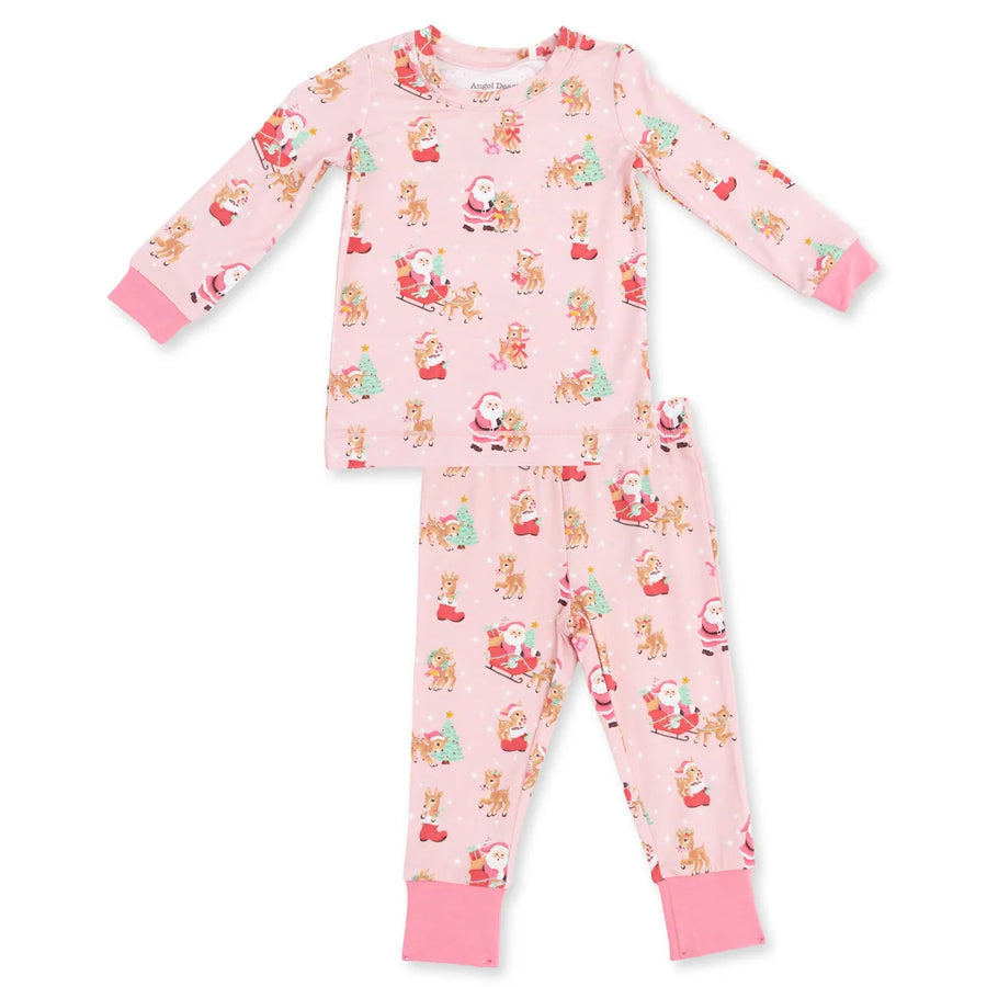A two-piece children's pajama set featuring a long-sleeve top and matching pants in light pink with a festive Christmas print of Santa Claus, reindeer, and snowman faces. The set has solid pink ribbed cuffs and collar on the top, and solid pink ribbed ankle cuffs on the pants.