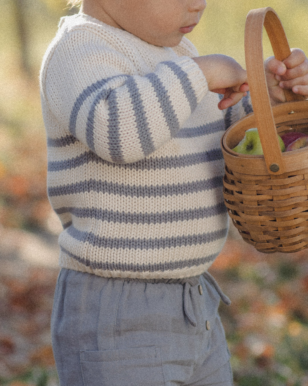 close up of the texture of the striped sweater and slate gray cotton pants. 