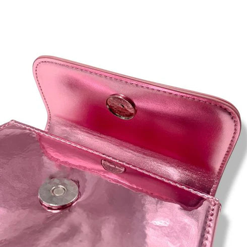 Pink metallic handbag, close up of a  button closure on a white background