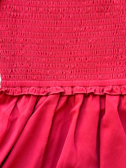 Close-up of a red dress with smocked top and gathered skirt.