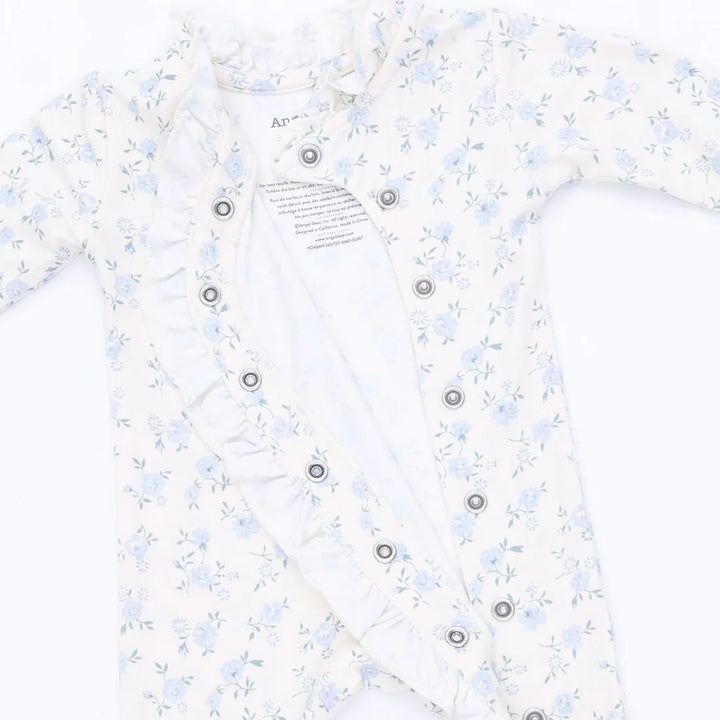 A baby long-sleeve romper in white with a light blue floral print, featuring ruffled trim along the neckline and front button closure.