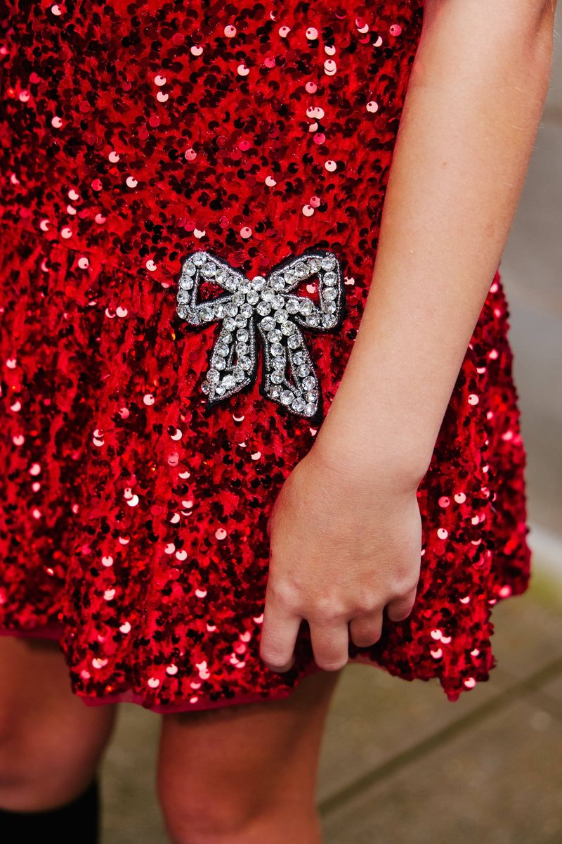 Red sequin dress with a silver bow detail on a blurred background