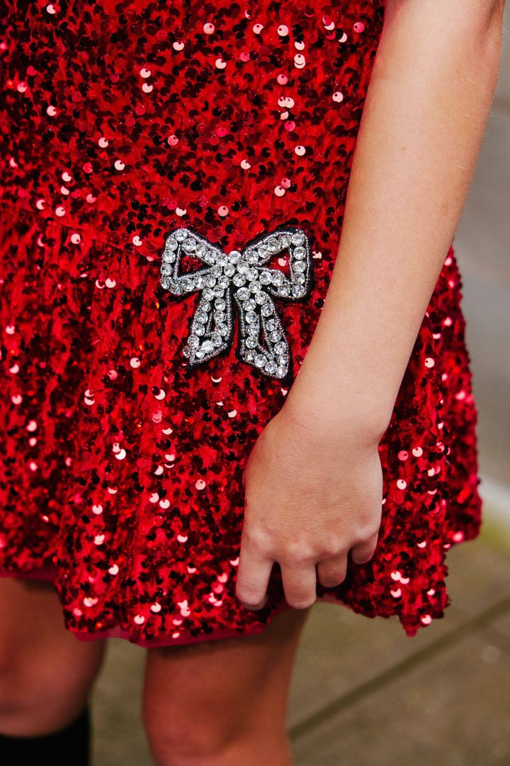 Red sequin dress with a silver bow detail on a blurred background