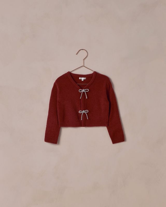 Red sweater on a hanger against a beige background
