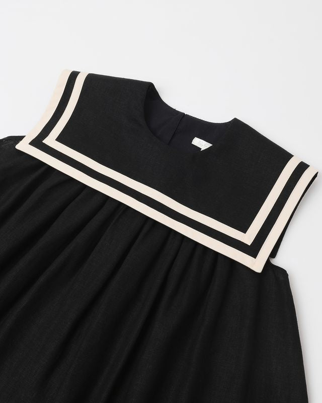 close up of the dress and fabrication. the dress is black with whtie piping along the oversized collar. 