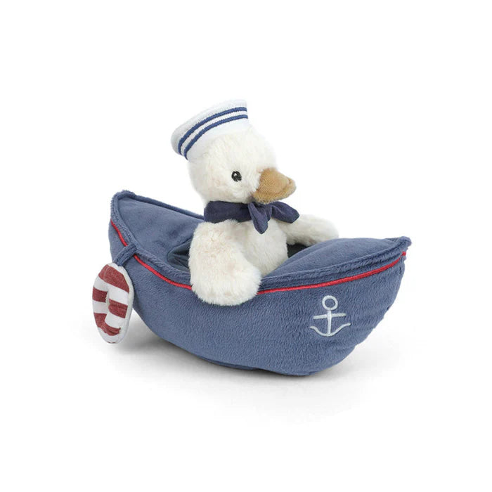 Stuffed toy duck in a blue boat with an anchor on a white background