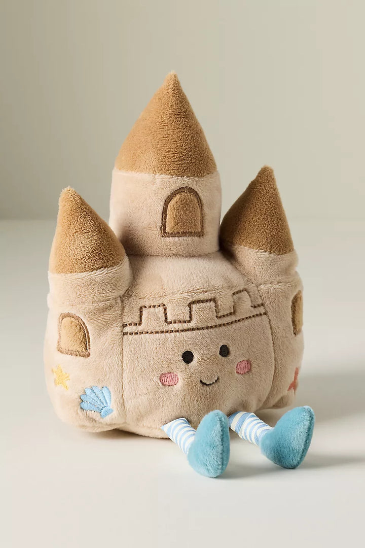 Plush toy sand castle with a face on a light background