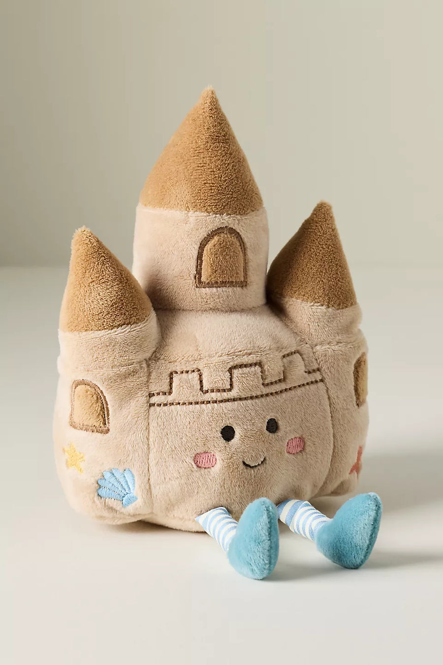 Plush toy sand castle with a face on a light background