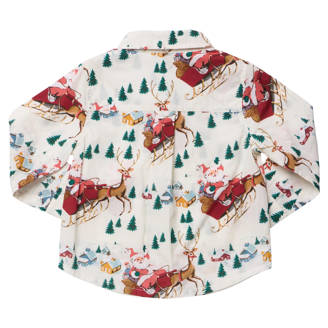 A long-sleeve button-up shirt with a festive Christmas print featuring Santa Claus in red sleeks, brown reindeer, green pine trees, and small houses on an off-white background.