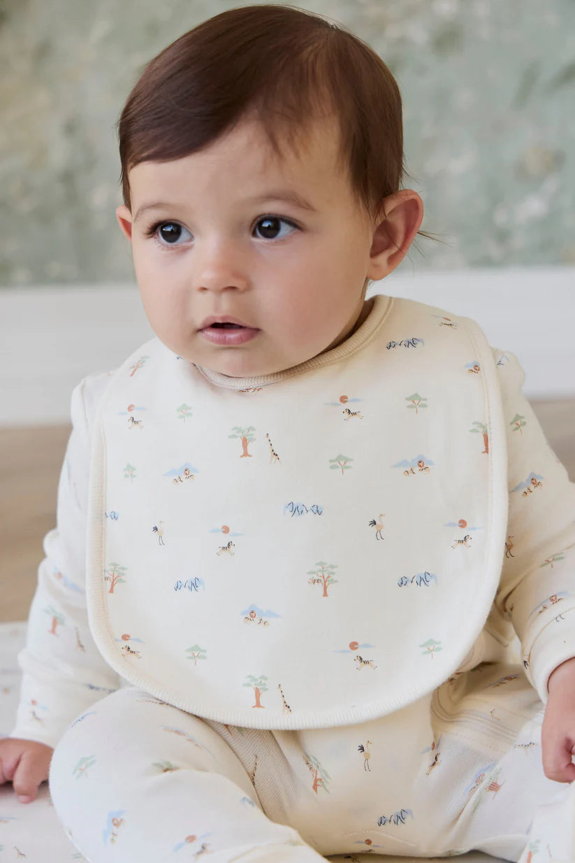 Baby wearing a bib with Savannah animal bib pattern sitting on a couch.