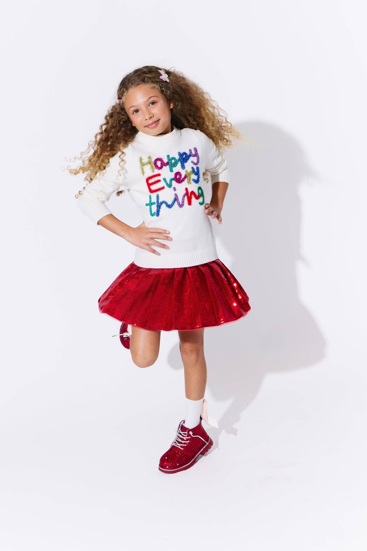 Young girl wearing a white t-shirt with colorful text and a red tutu skirt on a white background