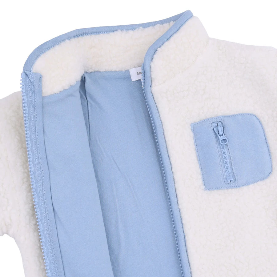 Close-up of a light blue and white fleece zip-up jacket, showing the white sherpa lining, light blue zipper trim, and a matching light blue zippered chest pocket.