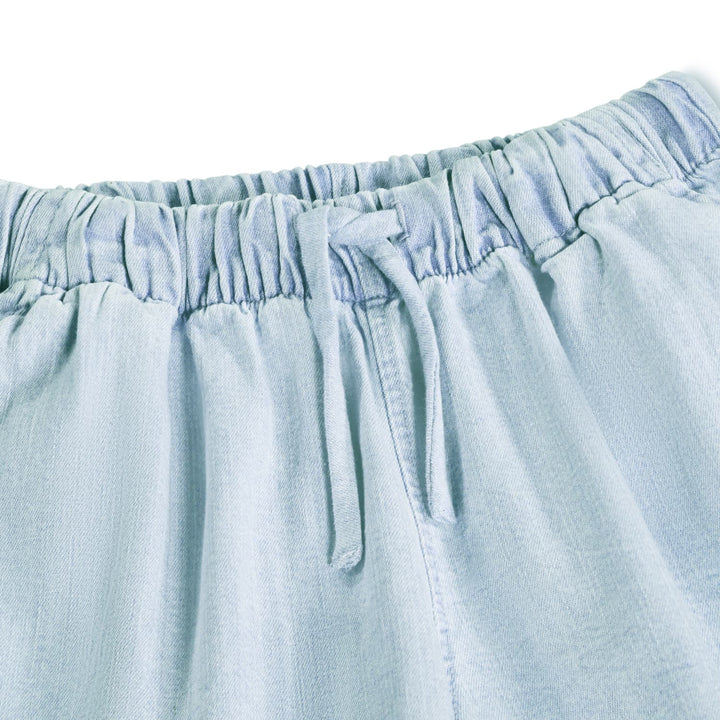 Close-up of light blue denim shorts with an elastic waistband.