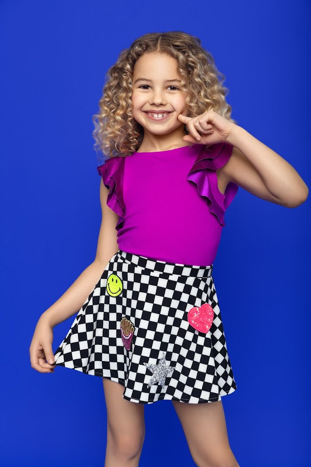 Young girl modeling the skirt and purple top. Black and white checkered skirt, smiley face patches, pink heart, silver sequin star and sequin french fries