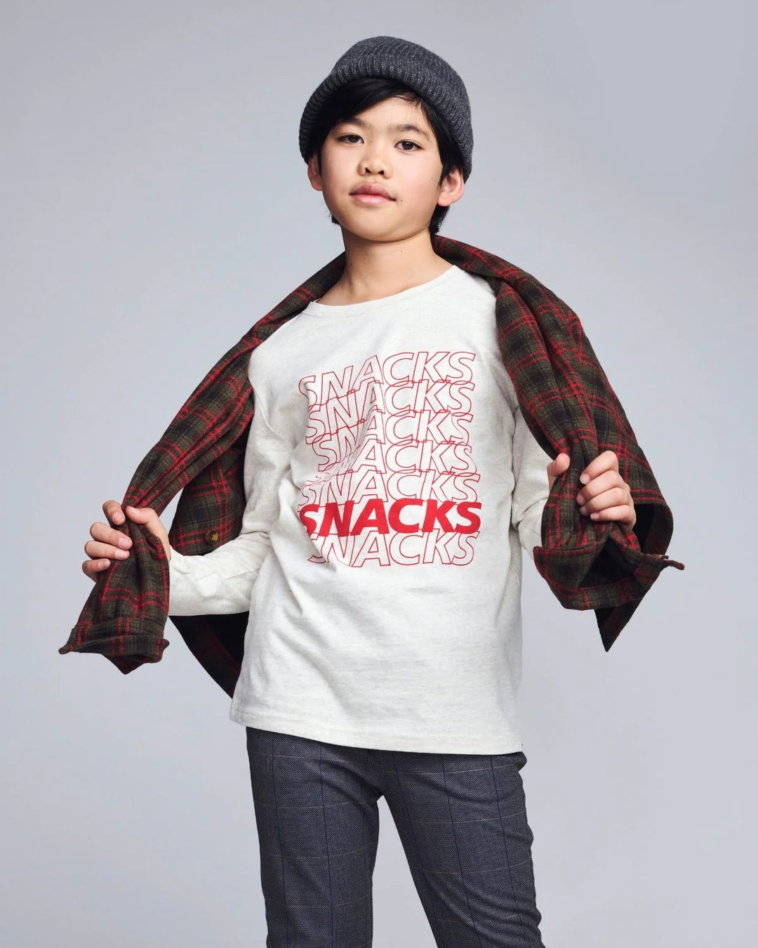 young boy wearing a long sleeve tee with the word 'snacks' written down the front. 