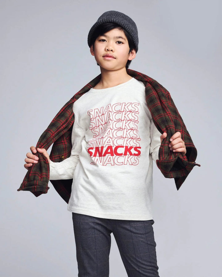 young boy wearing a long sleeve tee with the word 'snacks' written down the front. 