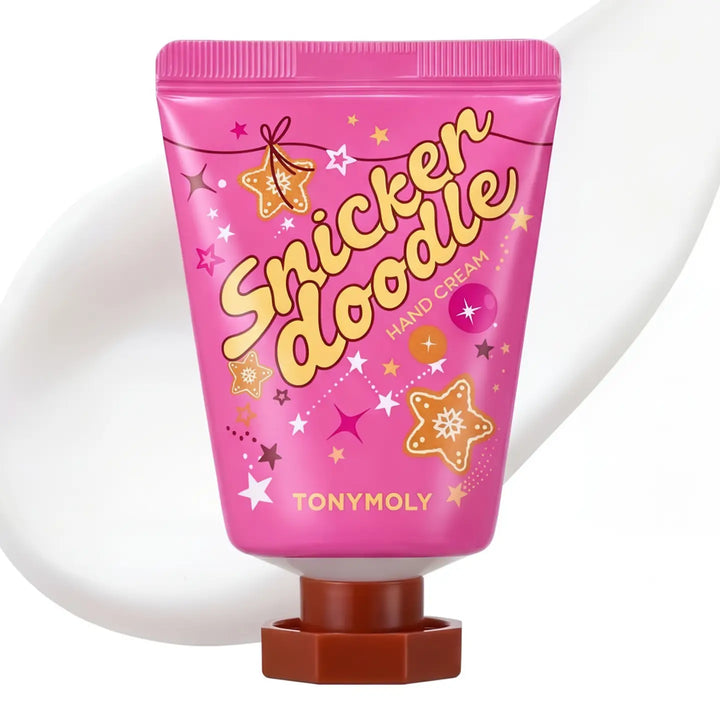 A tube of TONYMOLY Snicker Doodle Hand Cream in a vibrant pink packaging with gold and white lettering, decorated with star and cookie graphics, set against a white background with a soft shadow.